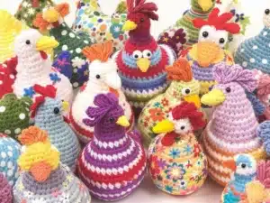 Colorful crocheted chickens in various patterns and designs.