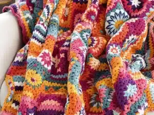 Couverture au point coquille crochetée colorée sur une chaise.