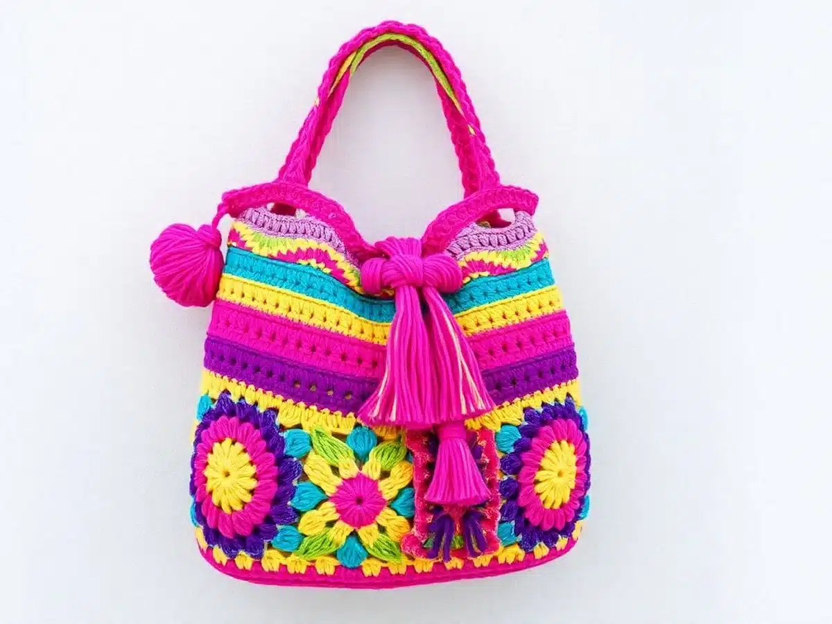Colorful crochet bag on textured background with stylish handle.