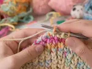 Hands crocheting vibrant treble stitches with colorful yarn.