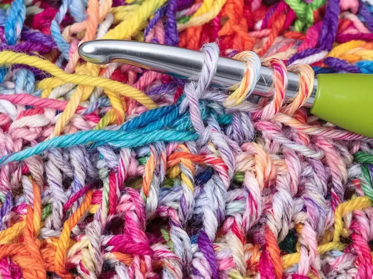 Colorful yarn and crochet hook with treble stitches.