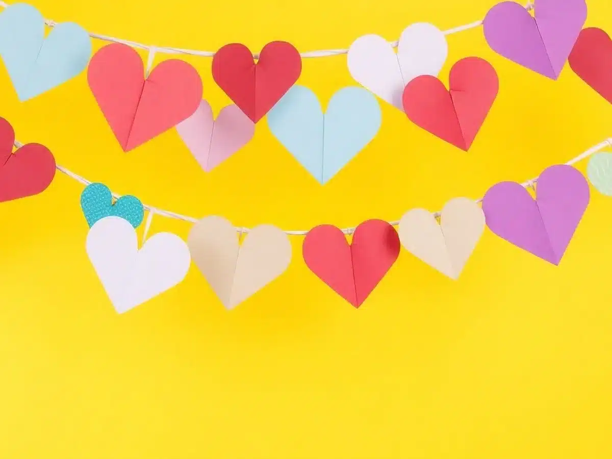 Colorful paper heart bunting hanging against a bright background.